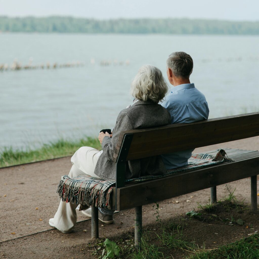 Senior couple sitting on a bench, enjoying a peaceful view by the lake.